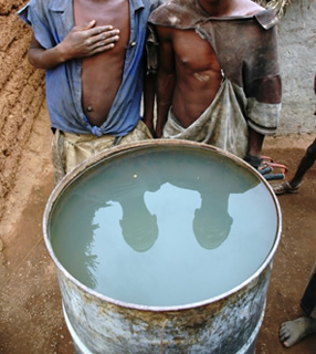 People standing with barrel of dirty water.